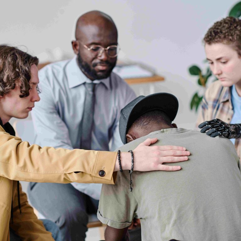 African teenage boy talking about his problems to people while they supporting him at psychology class